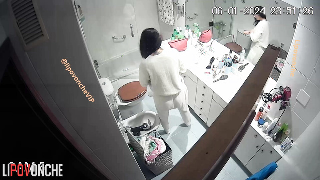 Brunette with big breasts tidies herself up in front of the mirror