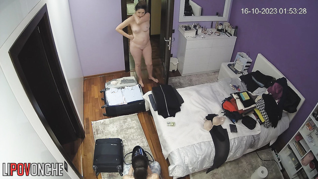 A girl packs a suitcase, and another one walks naked in front of her