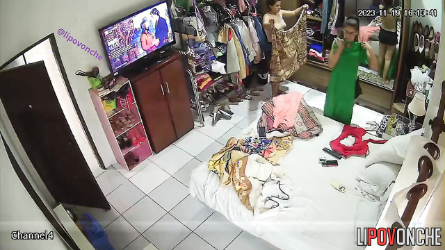 Two brunettes try on clothes near a mirror in a bedroom