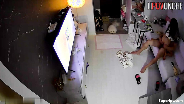 Asian couple having sex in cowgirl position and watching tv
