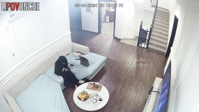Lady in burqa relaxing on the sofa in a huge living room