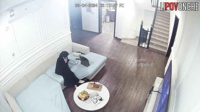 Lady in burqa relaxing on the sofa in a huge living room