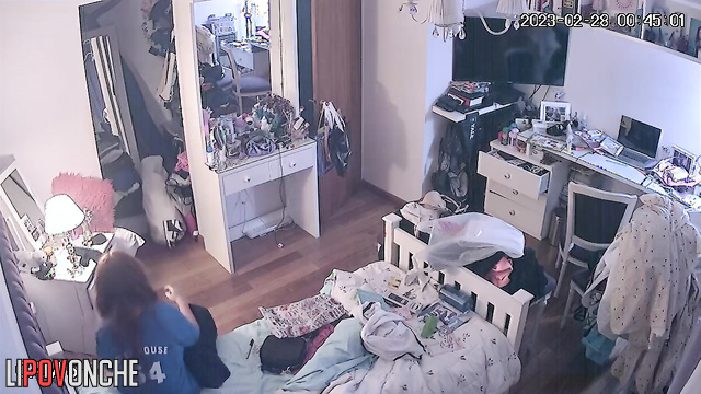 A girl with long red hair raises her hands to lift her firm tits in front of the mirror