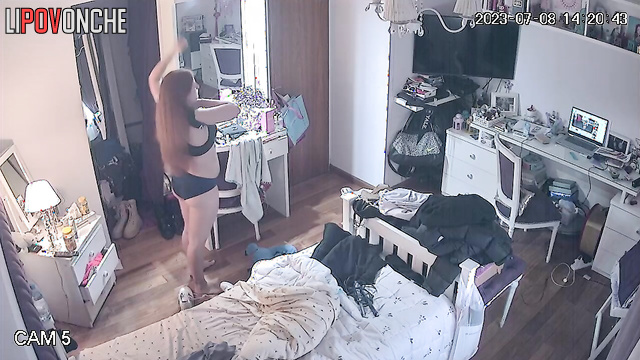 A red-haired cutie changes her bra, revealing her firm breasts