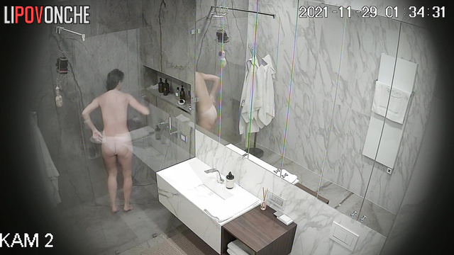 An sporty girl directs the warm stream of water from the shower onto her hairy pussy