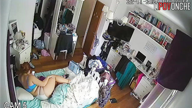 A red-haired college student is relaxing on the bed wearing only her lingerie