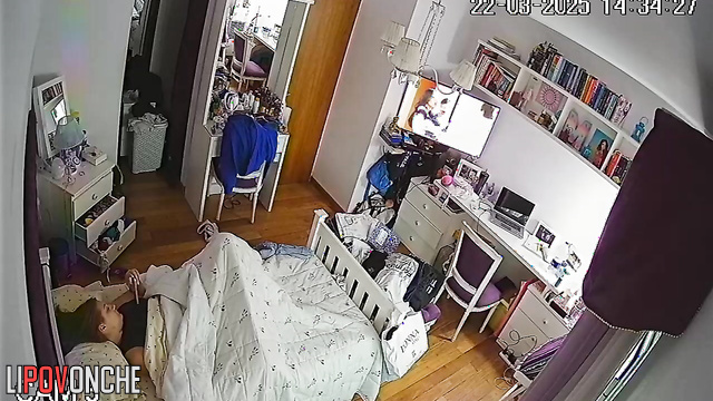 A bored redhead secretly masturbates under the covers while watching porn