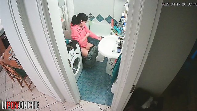 A girl, sitting on the toilet without panties, lifts her sexy legs high