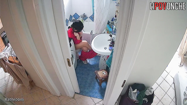 A beauty examines her shaved pussy while sitting on the toilet without panties