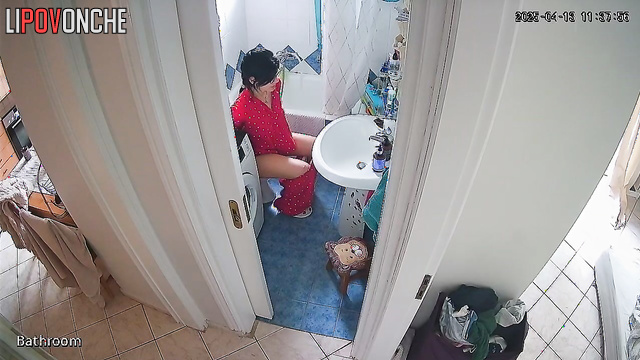 A beauty examines her shaved pussy while sitting on the toilet without panties