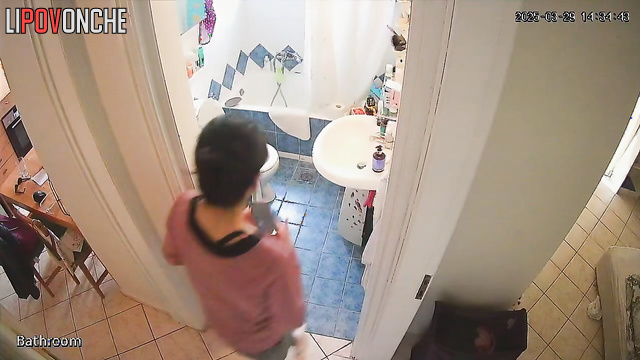 A cute housewife is chatting on the phone while peeing in the toilet