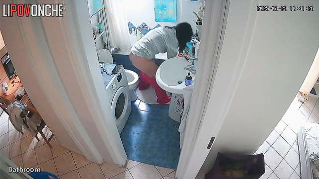 A young teacher wearing glasses pulls down her pants with one hand, exposing her ass