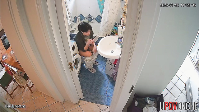 A gorgeous girl is watching porn on her phone while sitting on the toilet