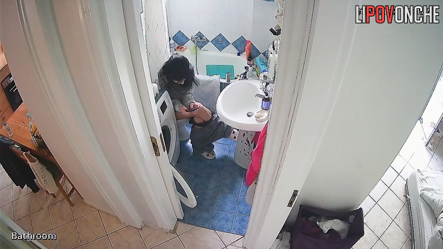 A housewife feeling under the weather sits on the toilet, phone in hand