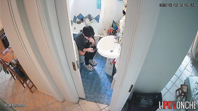A housewife is talking on the phone while sitting on the toilet with naked ass