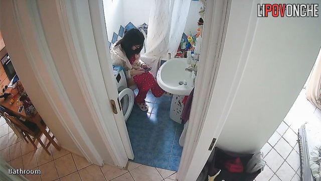 A brunette, sitting on the toilet, lifts her legs high, exposing her bare bottom