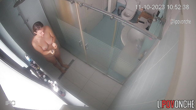 A charming mommy seductively strokes her tits while taking a shower